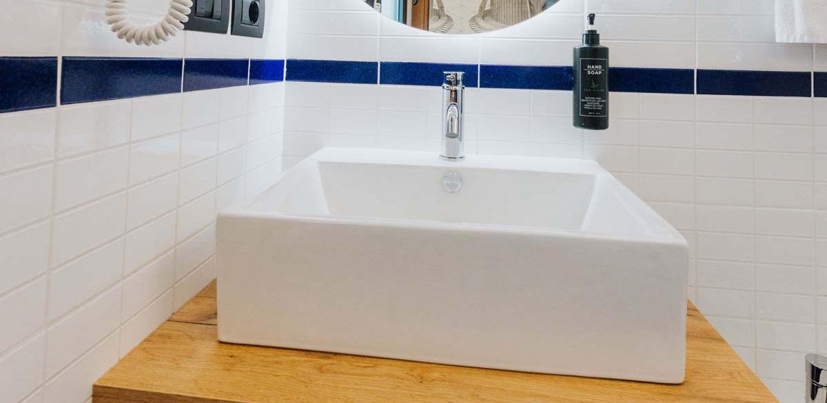Bagno moderno con lavandino elegante e dettagli blu, atmosfera fresca e pulita.